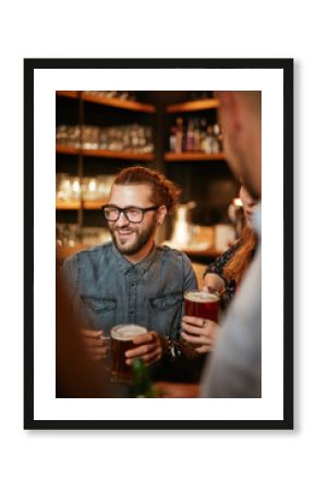 Group of friends drinking beer, chatting and having good time at pub. Night out.
