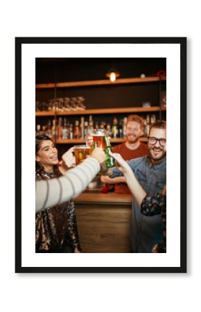 Friends standing in bar and toasting with beer.