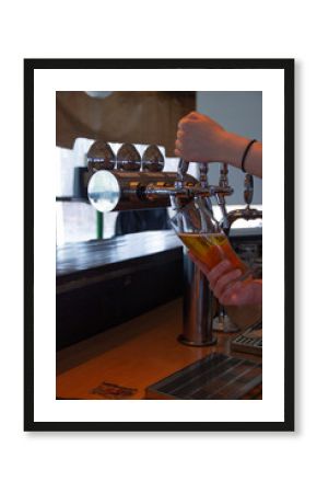 Pouring beer by young woman in polish pub 