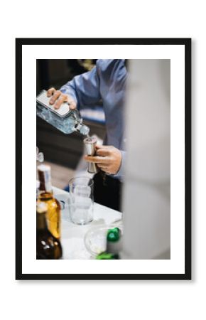 Detalle de manos de camarero sirviendo gintonic añadiendo ginebra en un dosificador