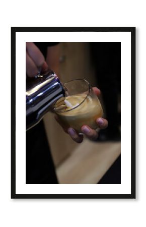 profesional barista elaborando un capuchino en una taza de cristal con leche con espuma