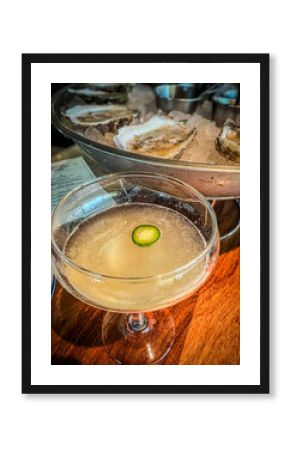 Handcrafted spicy cocktail with a dozen oysters on ice during happy hour