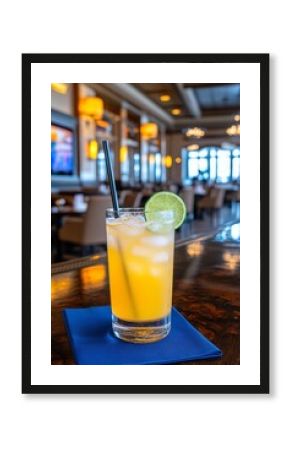  Vaso alto con un cóctel naranja brillante, decorado con una rodaja de lima y servido con hielo, colocado sobre una servilleta azul en un bar moderno. 