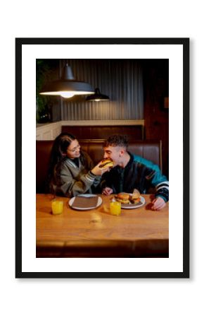 Happy couple enjoying a burger and orange juice together in a cozy burger joint