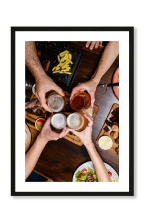 Friends toasting with beer over dinner table.