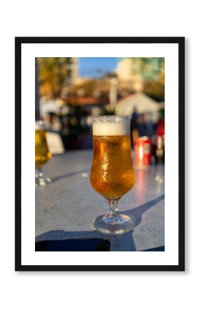 A refreshing glass of cold beer sits on an outdoor table, ready to be enjoyed in the sun.