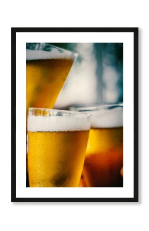 Close-up view of a three glass of beer in hand. Beer glasses clinking at outdoor bar or pub