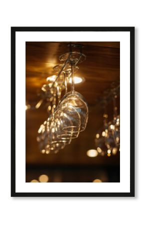 Stylish glasses for various alcoholic beverages hang over the bar in a modern restaurant. Glasses for wine, champagne.