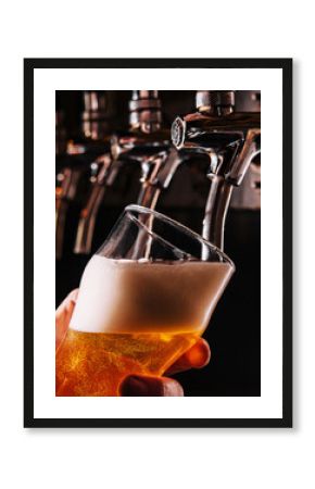 Close-up of barman hand at beer tap pouring a draught lager beer