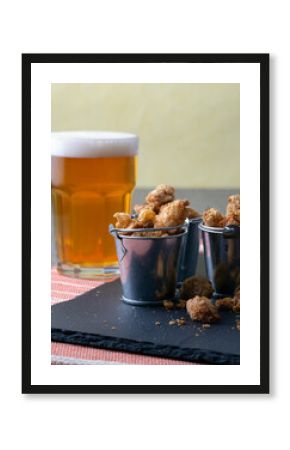 English pub snack of salted pork rind scratchings in miniature buckets with a glass of beer