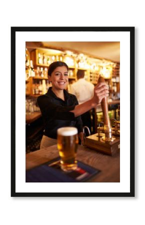 A young woman working behind a bar looking to camera