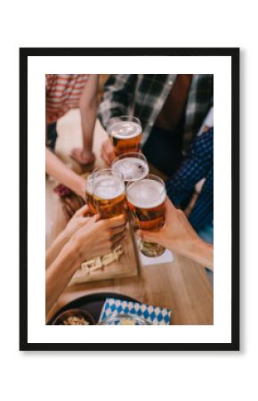 cropped view of multicultural friends clinking glasses of light beer in pub