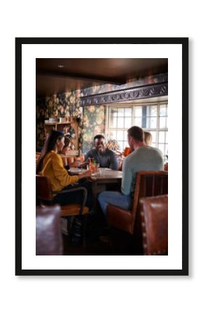 Group Of Friends Meeting For Lunchtime Drinks In Traditional English Pub