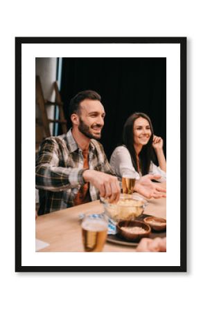 selective focus of young man taking chips from bowl while sitting with friends in pub