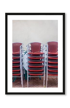 Rows of stacked Dutch pub terrace chairs in front of a white wall in the city of Kampen