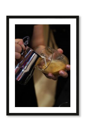 barista echando leche con espuma en una taza de café para elaborar un capuchino