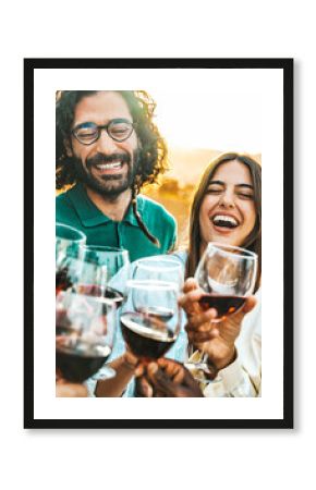 Happy friends toast with red wine at a vineyard - Group of young people enjoying happy hour at rooftop winery bar - Gathering and beverage life style concept  