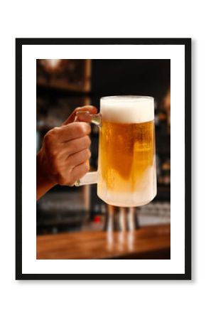 Hand holding cold beer in a pub