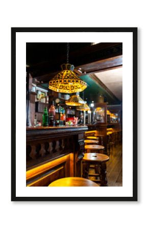 Warm lighting illuminating classic wooden bar counter and stools in traditional pub