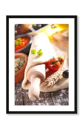 pizza dough with rolling pin and ingredients