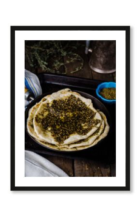 Freshly baked flatbread with mixed spice and herbs - zaatar or zatar on vintage wooden background. Selective focus. Toned image