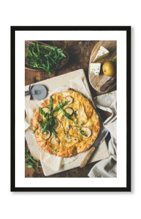 Pear blue cheese quatro formaggi pizza garnished with arugula on rustic wood, table top view, toned image