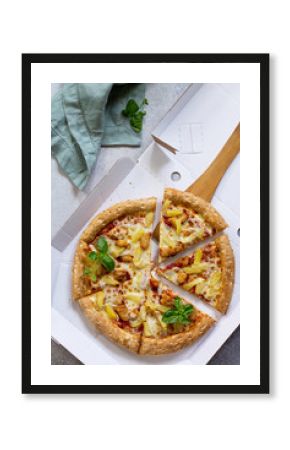 Pizza Hawaiian in a cardboard box on a light stone or concrete background. Pizza delivery.