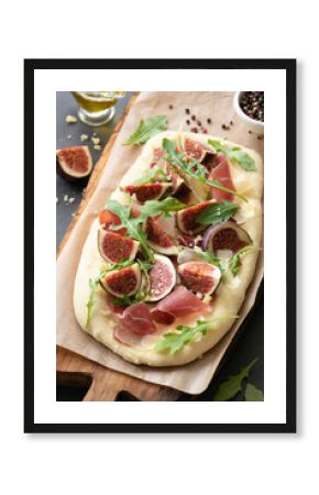 Pizza or flatbread with fig, prosciutto, cheese, arugula on wooden serving board. Selective focus