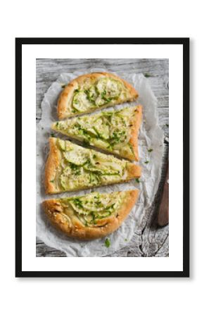 pizza with zucchini, onions and mozzarella on a light wooden background