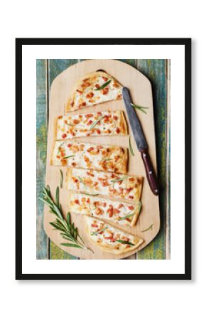 Tart Flambe or Flammkuchen on wooden cutting board, traditional Alsatian pie, rustic style, top view