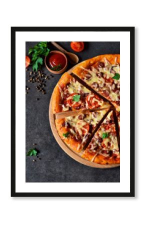 Home pizza with salami, tomato and cheese on a black background