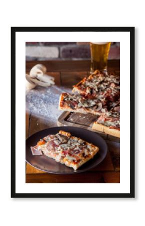 Slice of rectangular oven pizza served on wooden plate