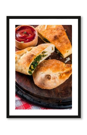 Italian food, closed pizza calzone with Spinach and Cheese, wooden background, copy space
