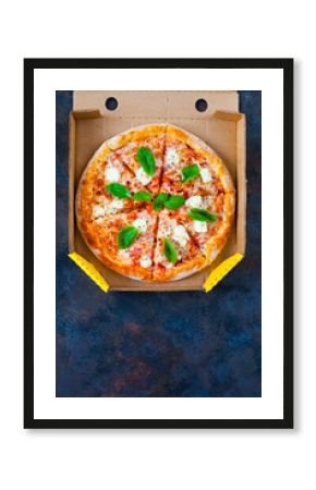 Homemade pizza with tomatoes, mozzarella and basil. Top view with copy space on dark stone table.
