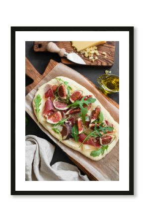 Flatbread pizza with ham, figs, arugula on wooden board. Top view