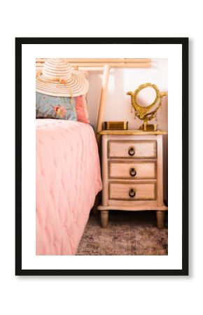 Stylish women sun hat lying on the bed next to the nightstand with a mirror. Elegance in a feminine style. Interior, Retro