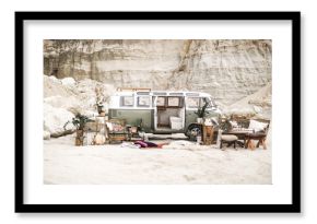 Wedding decor in boho rustic style. Green hippie bus, decorated sofa, armchair, carpets, pillows, table with candles, succulents, plant decoration on the background of canyon landscape