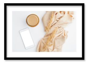 Modern minimal home office desk with beige blanket, cup of coffee, dry flowers and smartphone with blank screen mockup. Hygge or boho style women's workspace. Top view, flat lay.