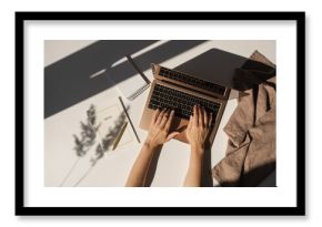 Aesthetic luxury bohemian minimalist home office workspace desk. Woman working on laptop computer. Notebook, blanket, pampas grass with sunlight shadows. Flat lay, top view work, business concept