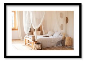 hygge decor at home. interior white bedroom in boho  style with coffe table,straw lamp and comfortable bed with pillows, copy space. bed with flowing white curtains. Cozy scandinavian decoration room