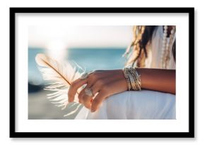 Woman with boho jewellery holding a feather in her hands close up. Spirituality, harmony and connection with nature concept.