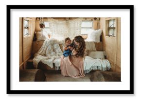 Mother and daughter cuddling and laughing in boho studio setup