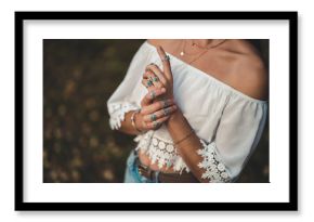 Fashionable boho chic woman in a white short blouse and with silver turquoise jewelry. Boho fashion. Stylish girl with silver rings using hippie style.