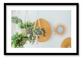 Modern minimal Scandinavian home interior design. Straw round decor with hanging flower pots with green plants on the white wall background. Eco natural trendy style. Copy space.