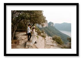 Side view of happy young couple in stylish wedding clothes standing together against mountainous landscape of Morro de Labella in Spain