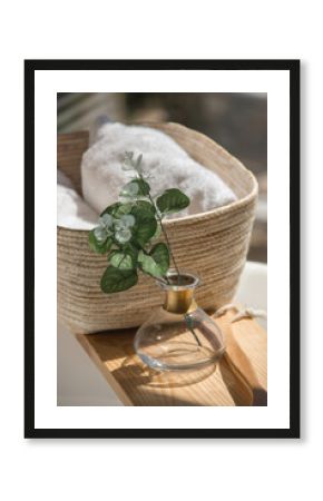 close-up white bath towels in a wicker basket next to accessories on a wooden shelf in the white bathroom at morning