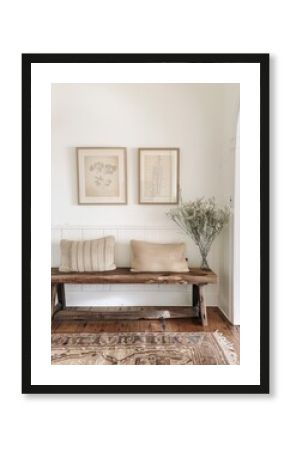 Modern entryway with a rustic wooden bench, two frames, and white wall in a farmhouse and boho home design