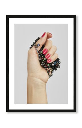 HAND WITH RED NAIL POLISH HOLDING JEWELS
