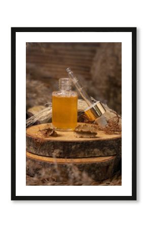 Opened cosmetic dropper bottle filled with yellow serum on wood near natural boho decor