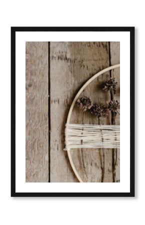 Stylish boho autumn wreath with dry flowers flat lay. Wooden hoop, thread and dry herbs on rustic wooden background. Modern floral arrangement and handmade decor